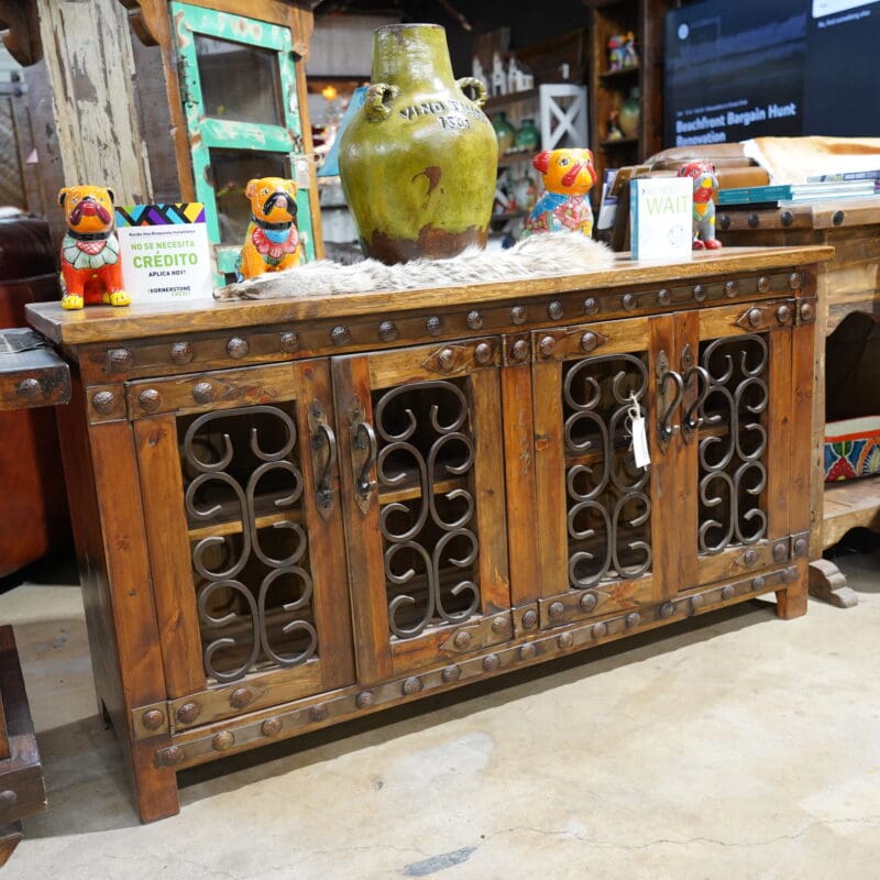 A wooden buffet with metal doors and iron work.