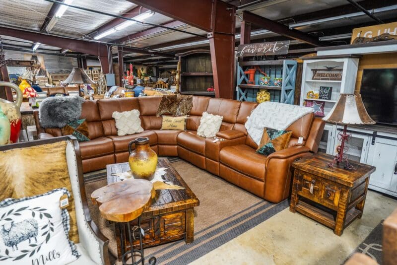 A living room with brown leather furniture and wooden tables.