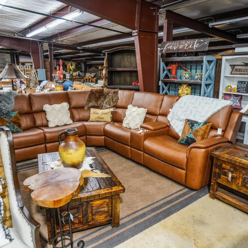 A living room with brown leather furniture and wooden tables.