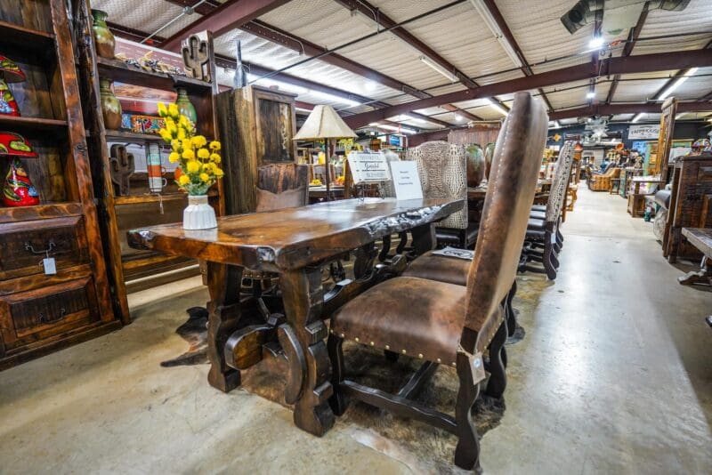 A table and chairs in a room with many items.