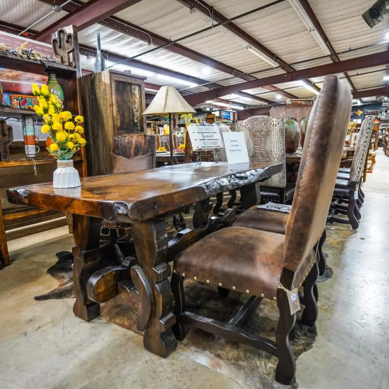 A table and chairs in a room with many items.