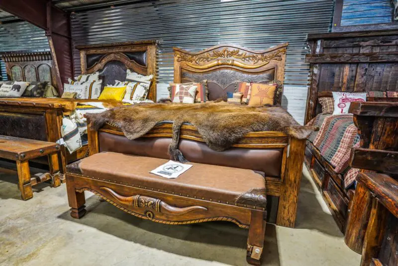 A bed with leather headboard and footstool in the background.