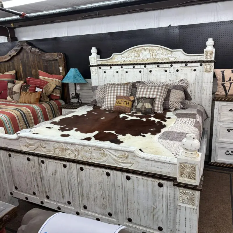 A bed with white wood and brown cow hide.