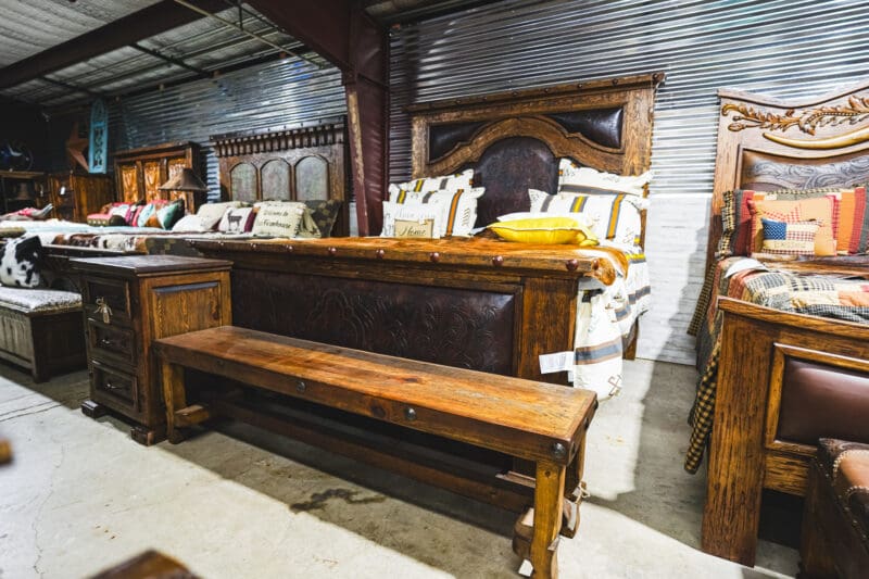 A wooden bed frame with leather headboard and bench.