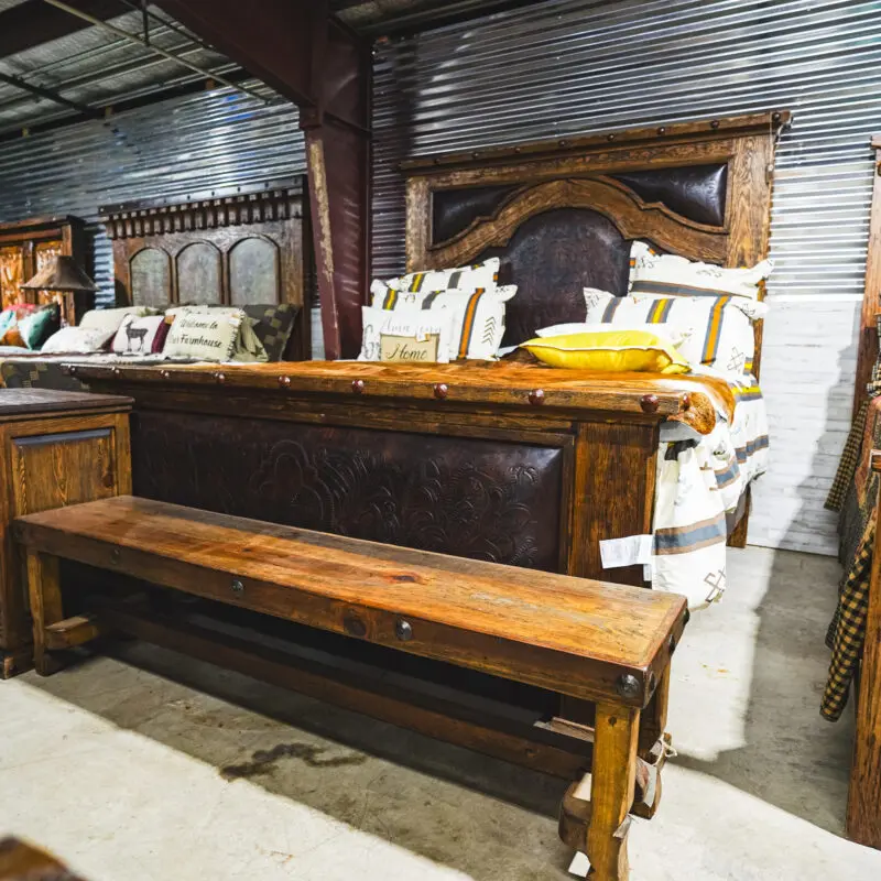 A wooden bed frame with leather headboard and bench.