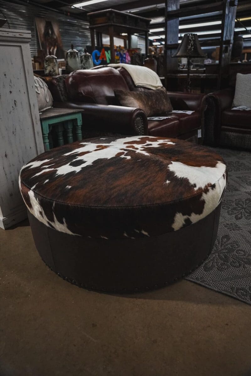 Cowhide ottoman with brown trim.