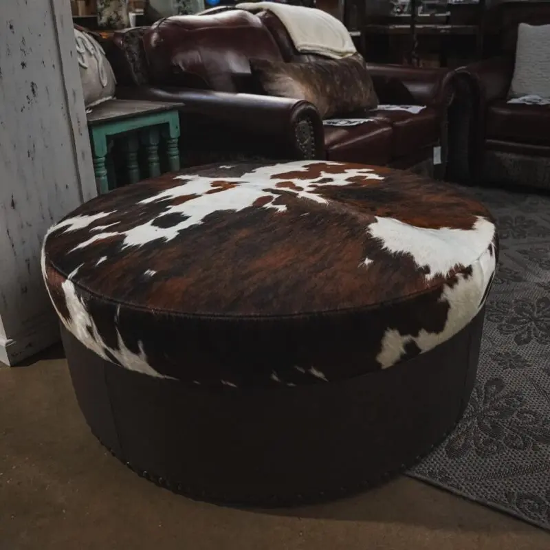 Cowhide ottoman with brown trim.