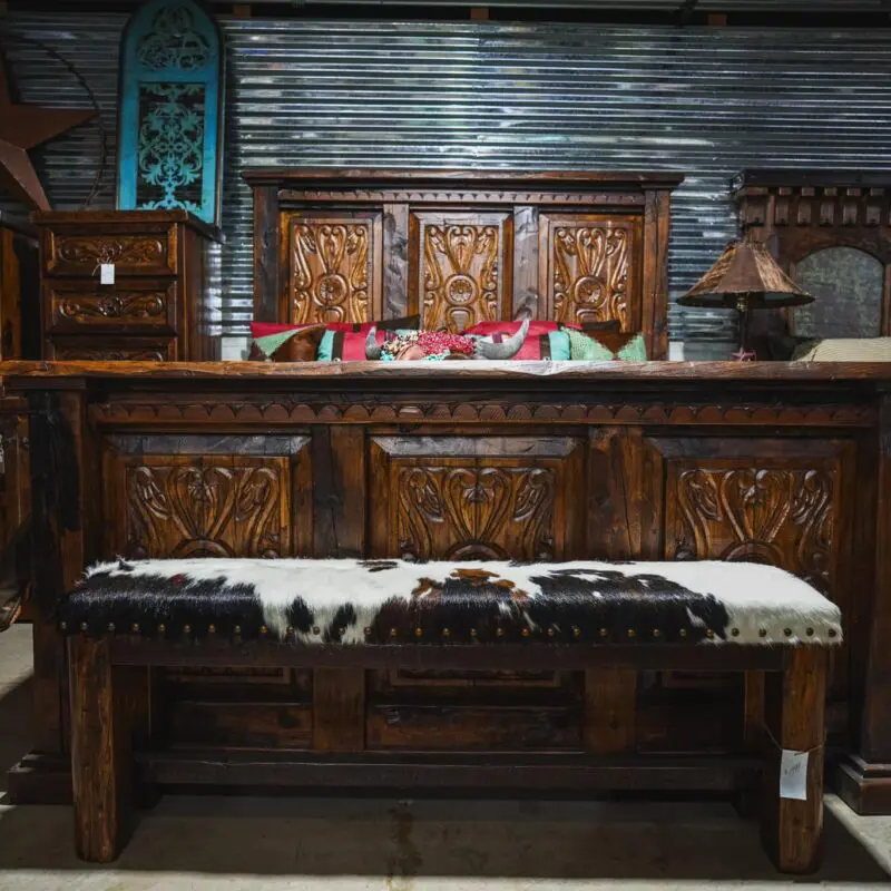 Carved wooden bench with cowhide seat.