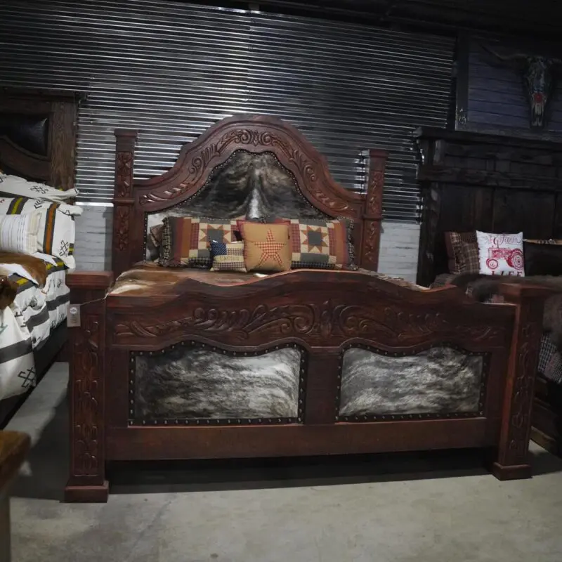 Carved wooden bed with cowhide headboard.