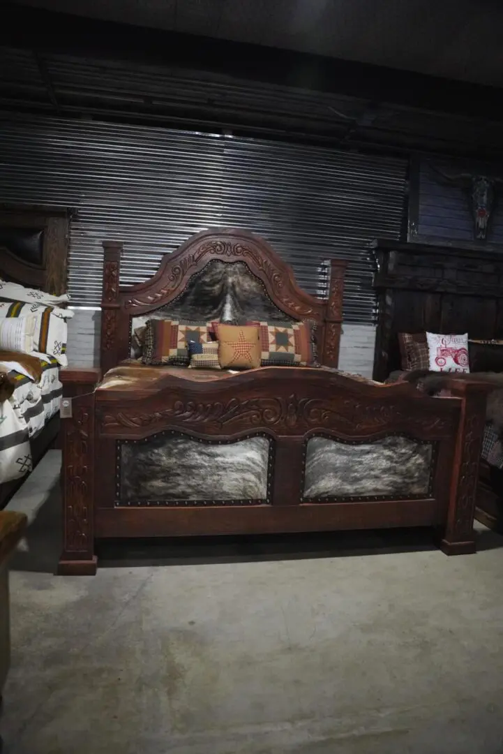 Carved wooden bed with cowhide headboard.