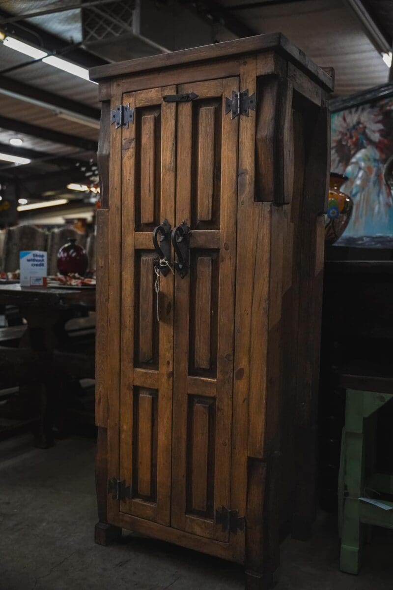 Wooden cabinet with ornate door and hardware.