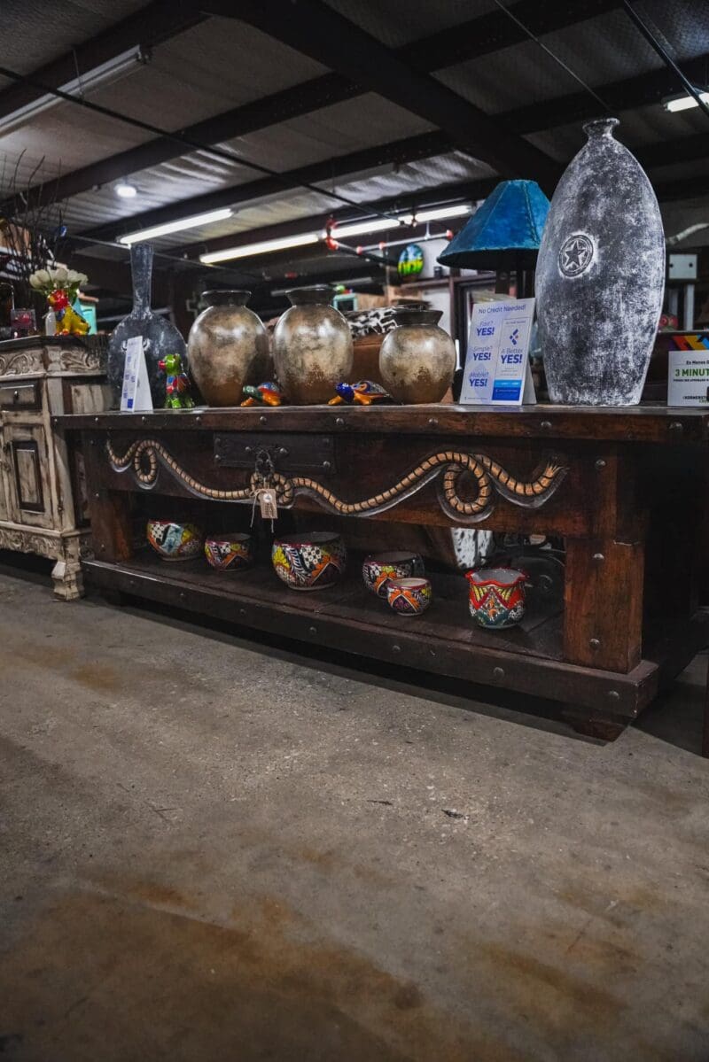 Ornate wooden table with pottery and decor.