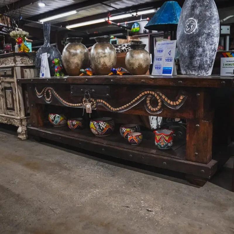 Ornate wooden table with pottery and decor.