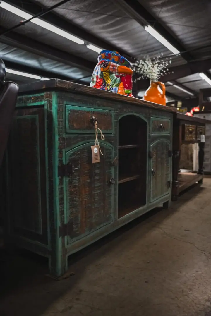 Distressed turquoise cabinet with shelves and drawers.