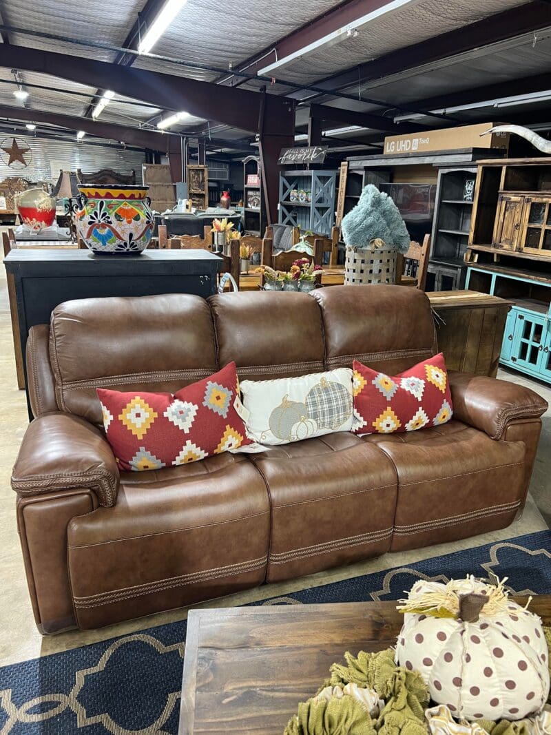 Brown leather couch with pillows in a store.