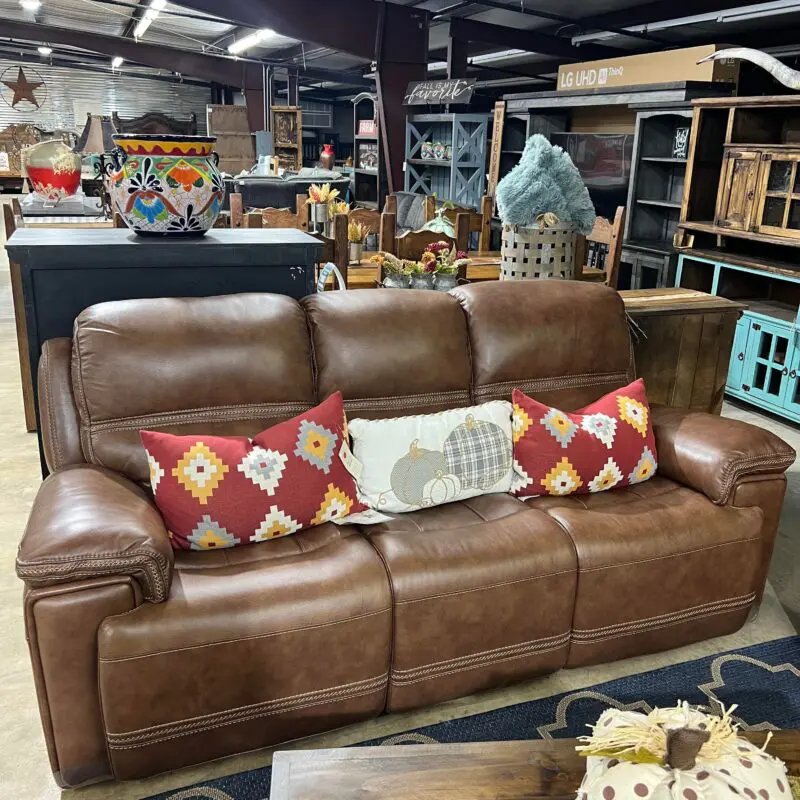 Brown leather couch with pillows in a store.