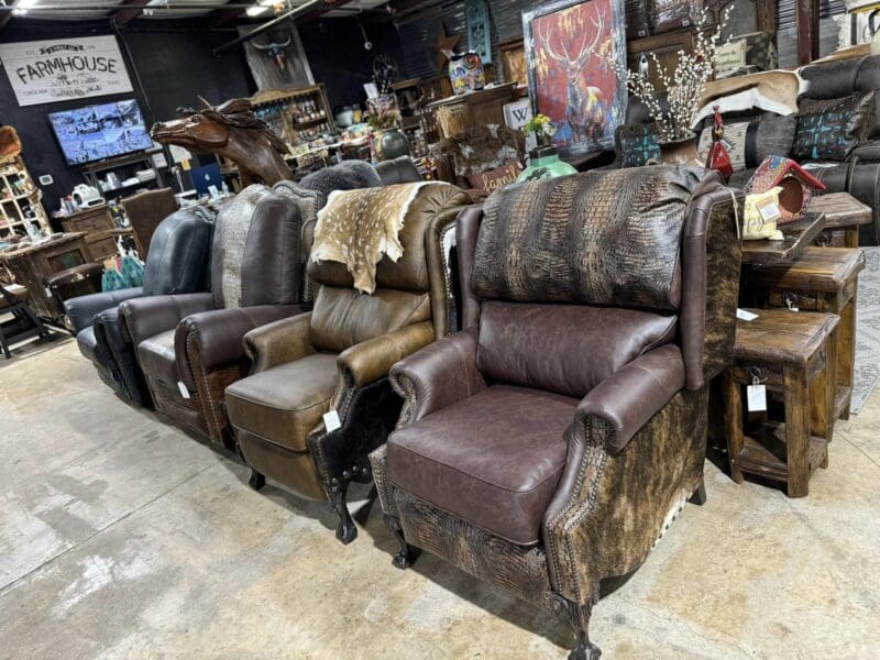 Four brown leather recliners in a store.