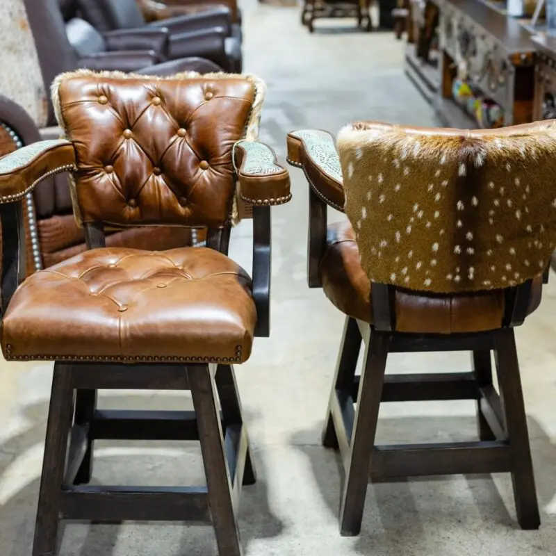 Two brown leather bar stools with wood legs.